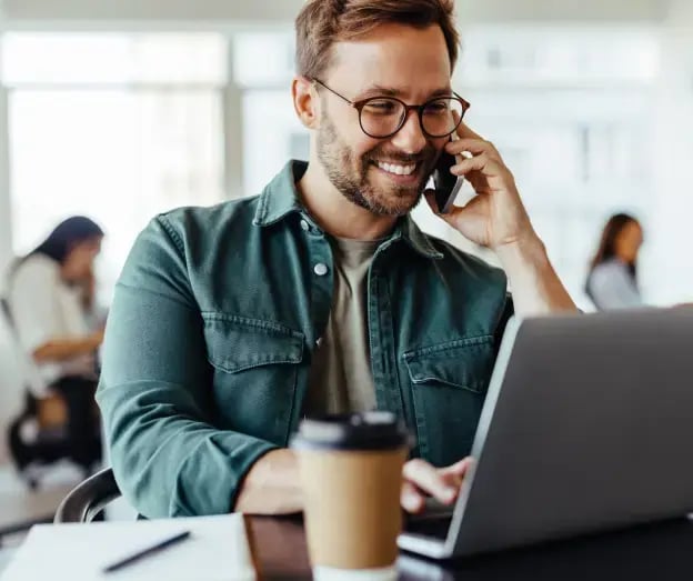 man on phone in front of laptop